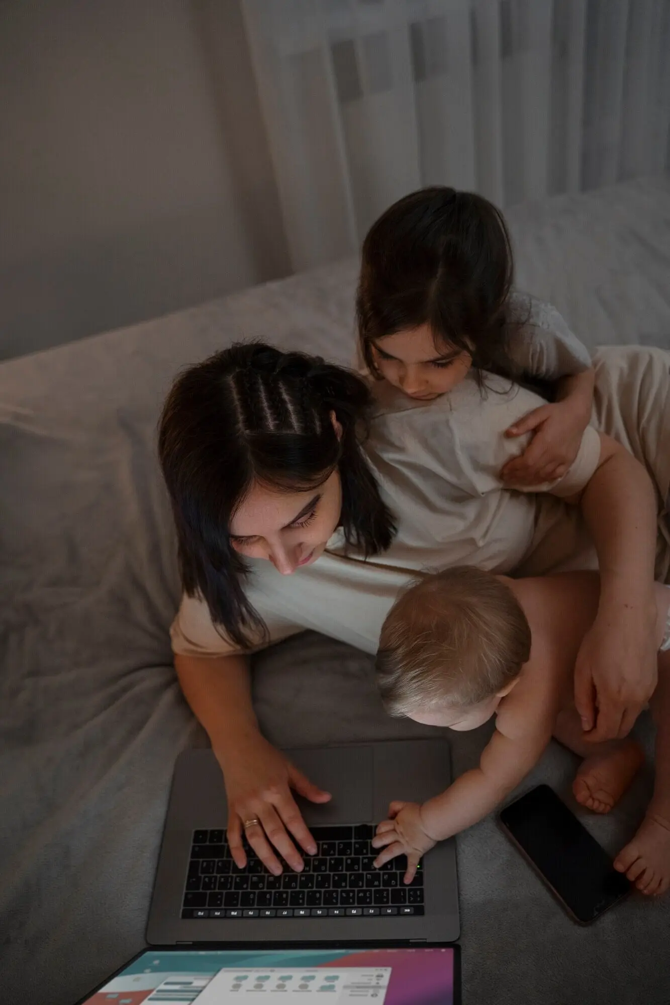 Blick von oben auf eine Mutter mit Laptop und Kindern